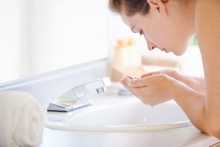 Woman washing her face with NEUTROGENA® to help keep skin clear