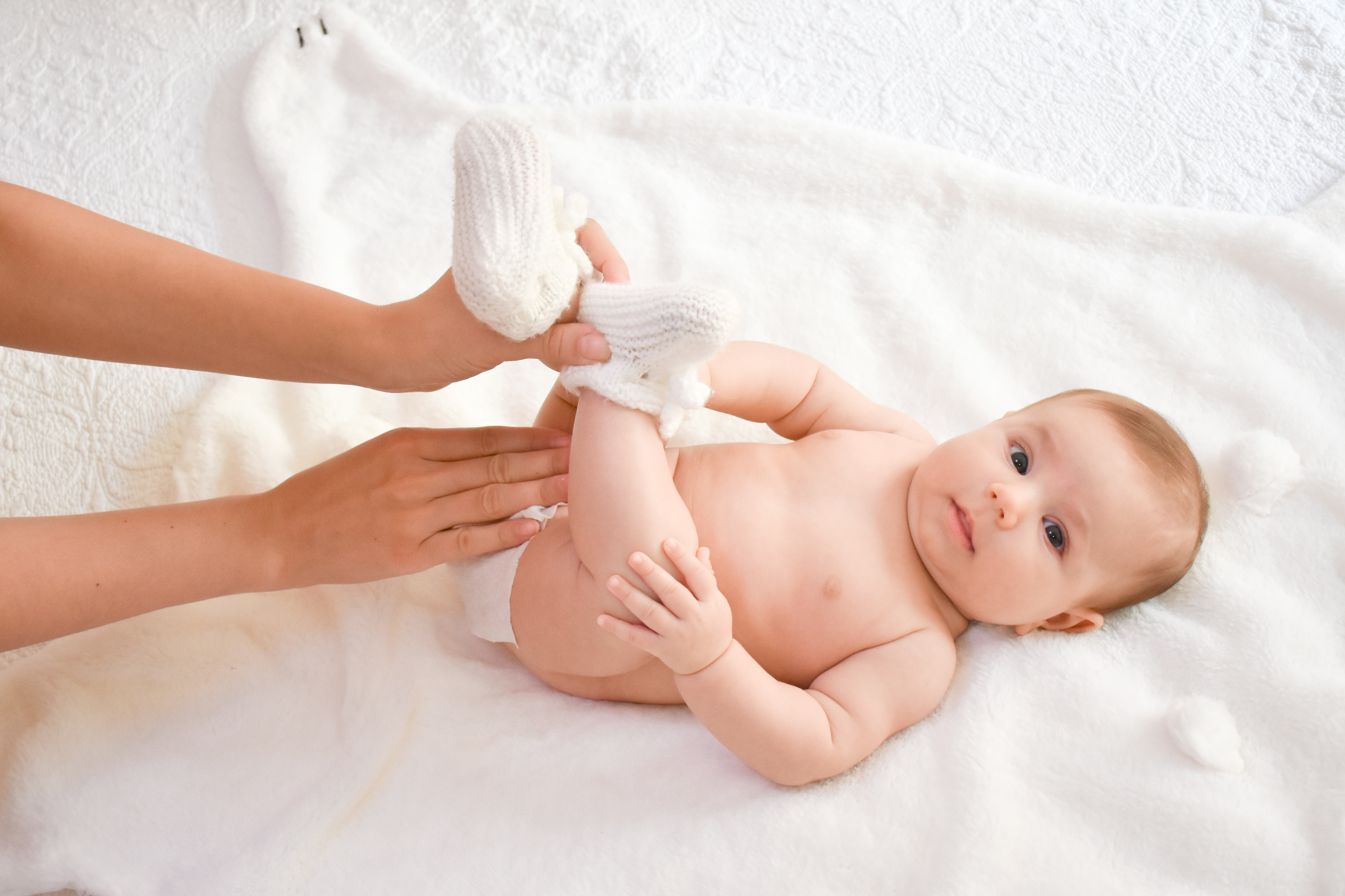 Mother changing her baby’s diaper in bed