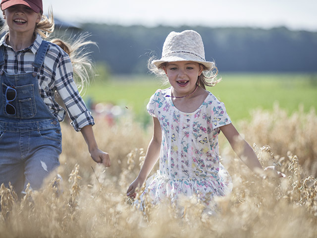 Sisters playing outside in tall grass