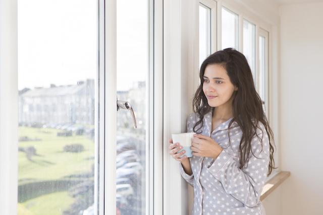 Woman standing by window with coffee