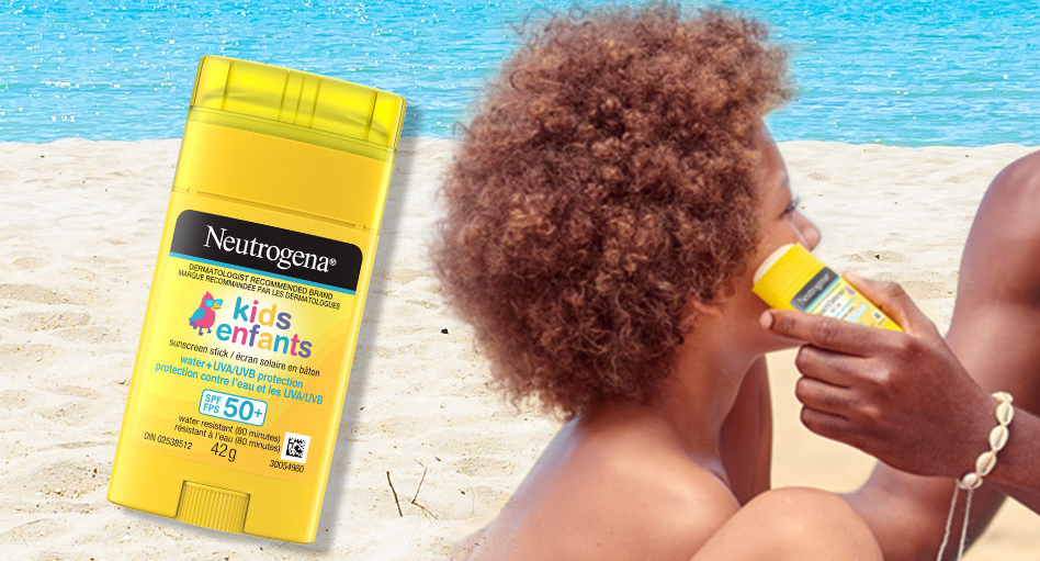 Père appliquant l’écran solaire en bâton pour enfants Neutrogena®, avec FPS 50+, sur le visage de son enfant à la plage.