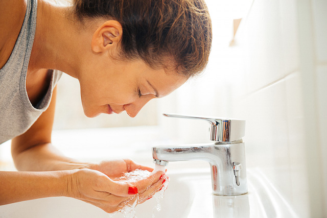 Femme se lavant le visage avec un produit NEUTROGENA® pour traiter et prévenir l'acné