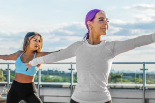 Two women doing yoga on a rooftop