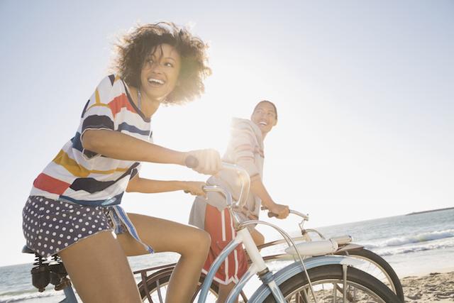 Jeune femme et jeune homme à vélo sur une plage ensoleillée