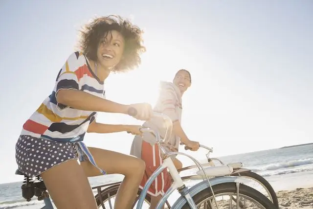 Jeune femme et jeune homme à vélo sur une plage ensoleillée