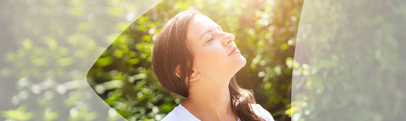 Young woman with eyes closed taking a breath of fresh air