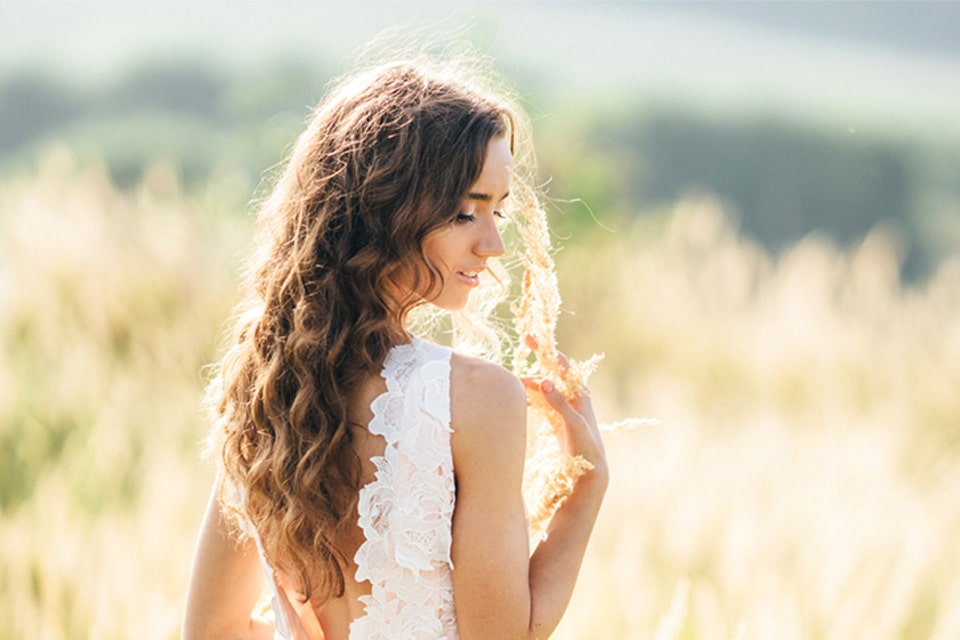 femme aux longs cheveux bruns ondulés posant la main sur son épaule