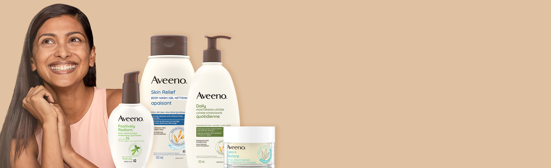 Une bannière montrant une femme souriante aux longs cheveux noirs lisses et quatre produits Aveeno® pour le corps et le visage