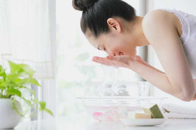 Woman splashing water on her face after using NEUTROGENA® sensitive skin products