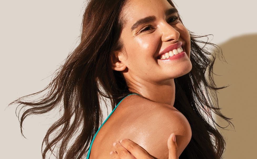 woman with long brown hair smiling against a beige backdrop