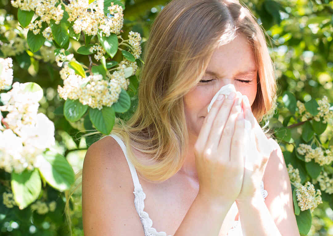 Woman sneezing into a tissue