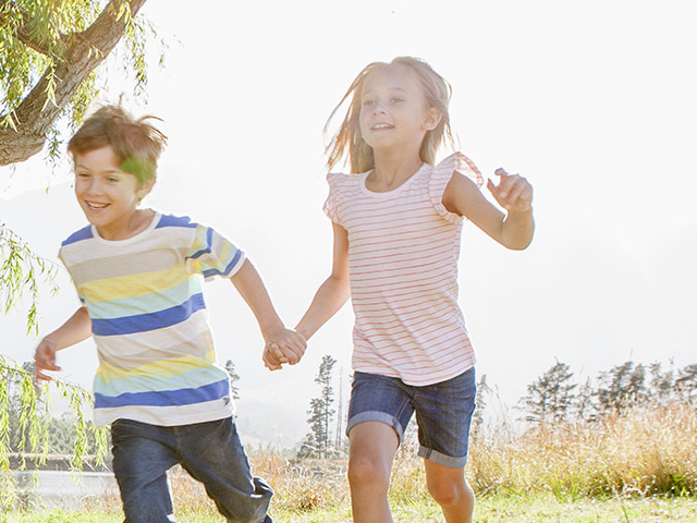 Siblings running in the grass outside