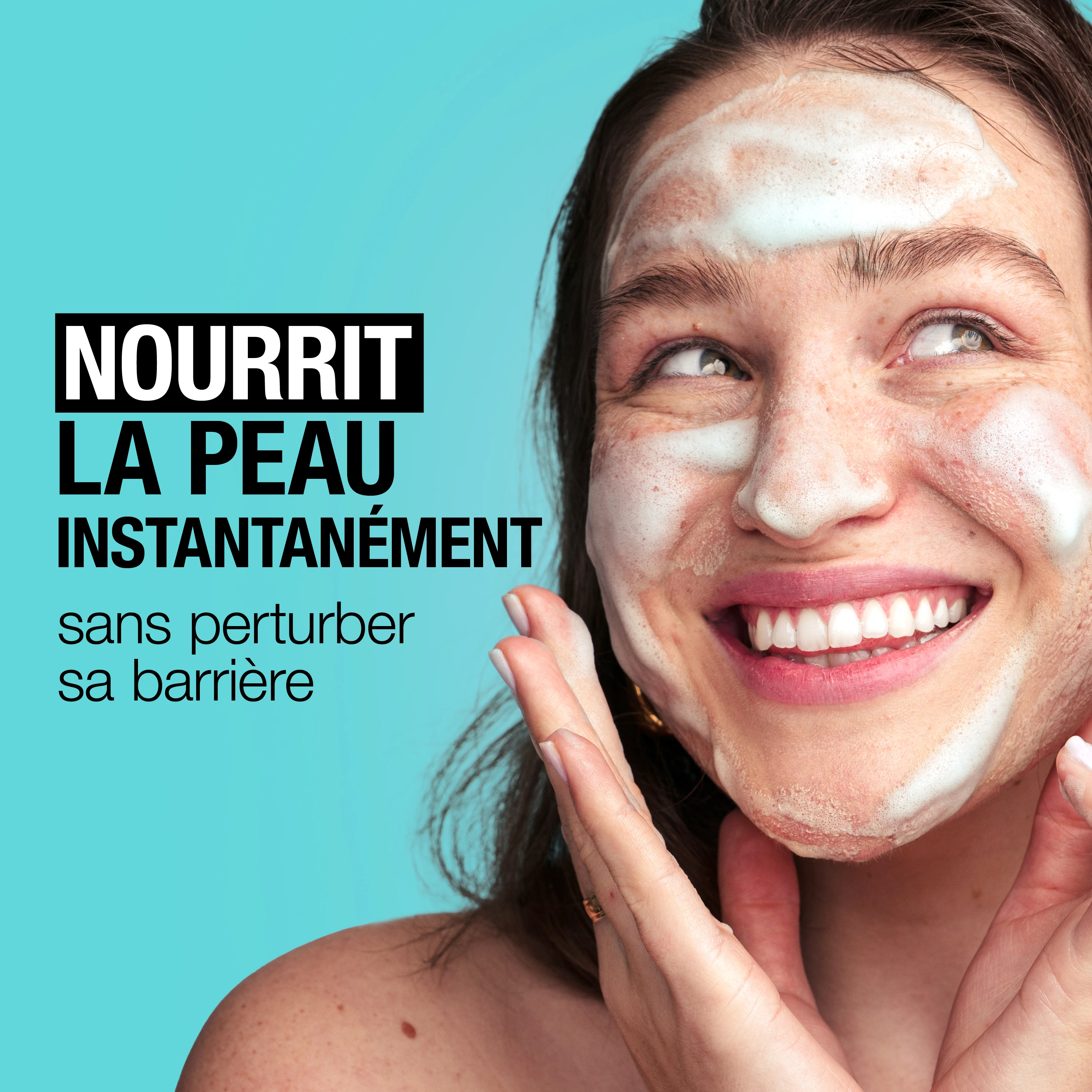 Une jeune femme se lavant le visage avec un nettoyant moussant tout en souriant.