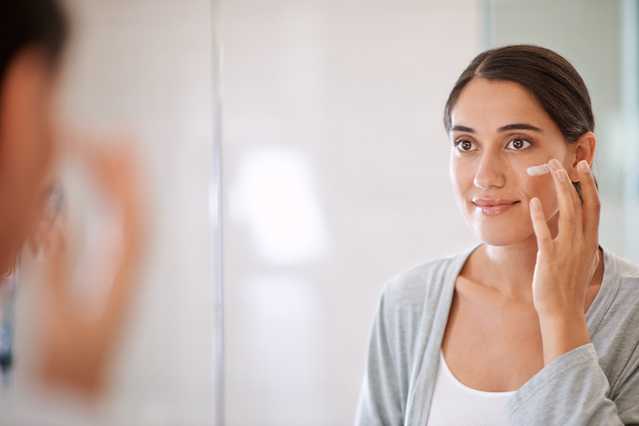 Woman applying NEUTROGENA® moisturizer to face