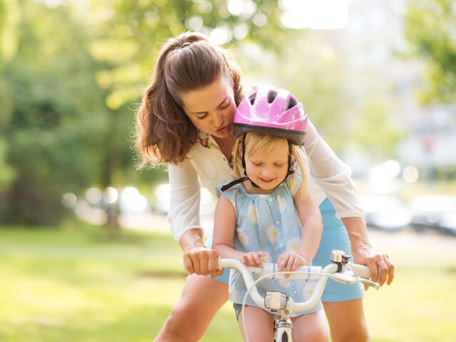 Mom helps daughter ride a bike