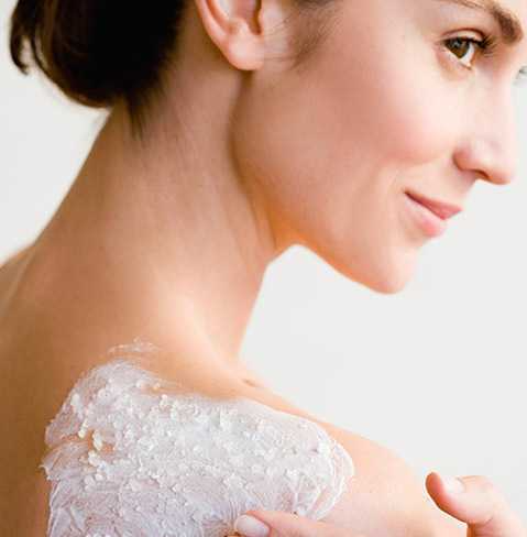 Woman lathering NEUTROGENA® body scrub on her shoulder.