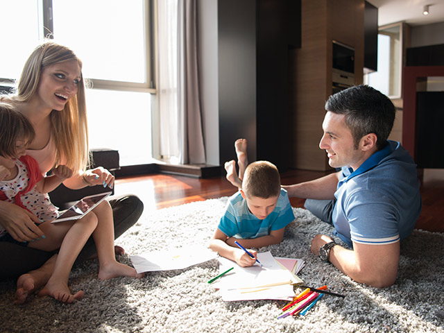 Une famille qui joue à des jeux de société à l’intérieur sur un tapis