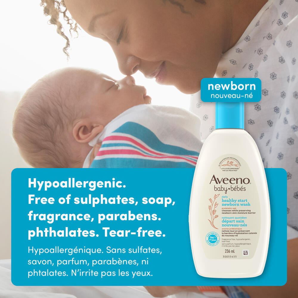 Front shot of Aveeno® Baby Healthy Start Newborn Wash squeeze bottle, 236mL, and a mom rubbing nose with her newborn baby in her arms in the background