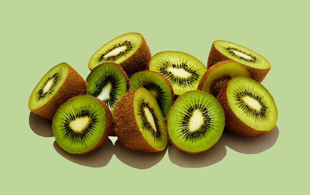 half kiwi fruit against a green background