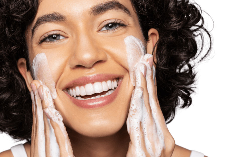 Woman smiling while applying a face cleanser on her face