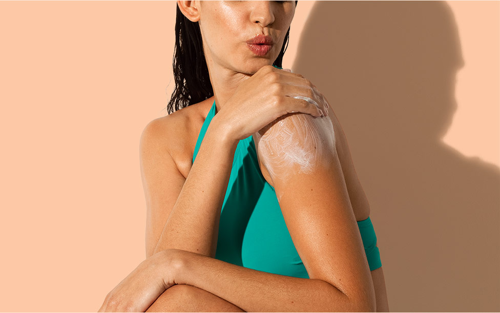 close up of woman putting aveeno sunscreen on her shoulder