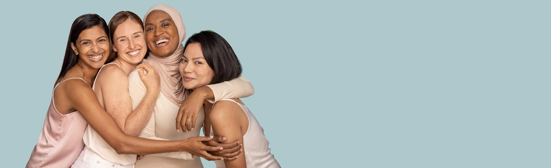 Banner including four women from different ethnicities, all smiling and hugging each other.