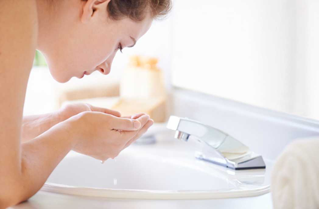 Woman washing her face with NEUTROGENA® to help keep skin clear