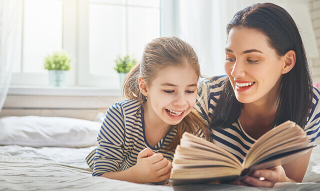 Une maman lisant un livre à sa fille dans un lit