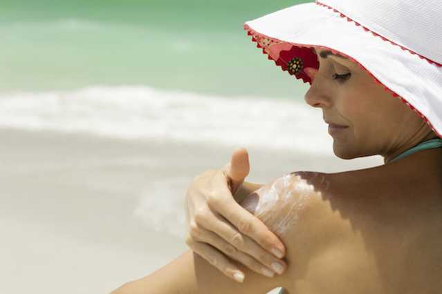 Woman applying NEUTROGENA® sunscreen to her left shoulder