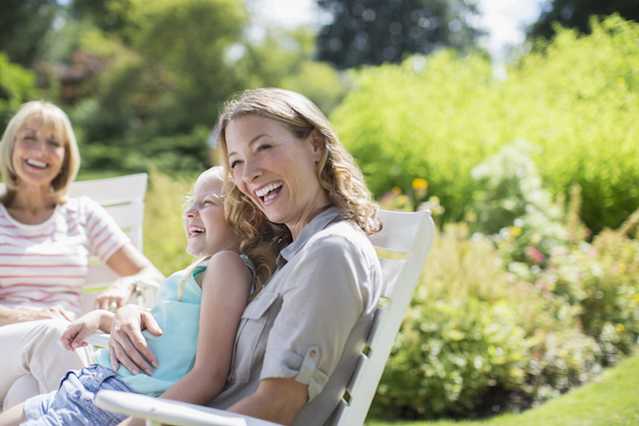 Femme souriante assise, en compagnie de sa famille, en plein air