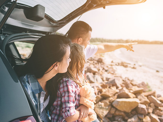 Family sitting in back of car on a beach