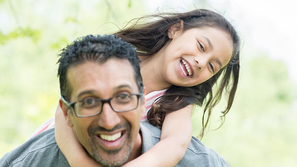 Girl laughing with father while on his back