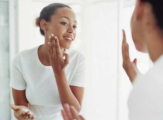 Woman moisturizing her face with NEUTROGENA® products