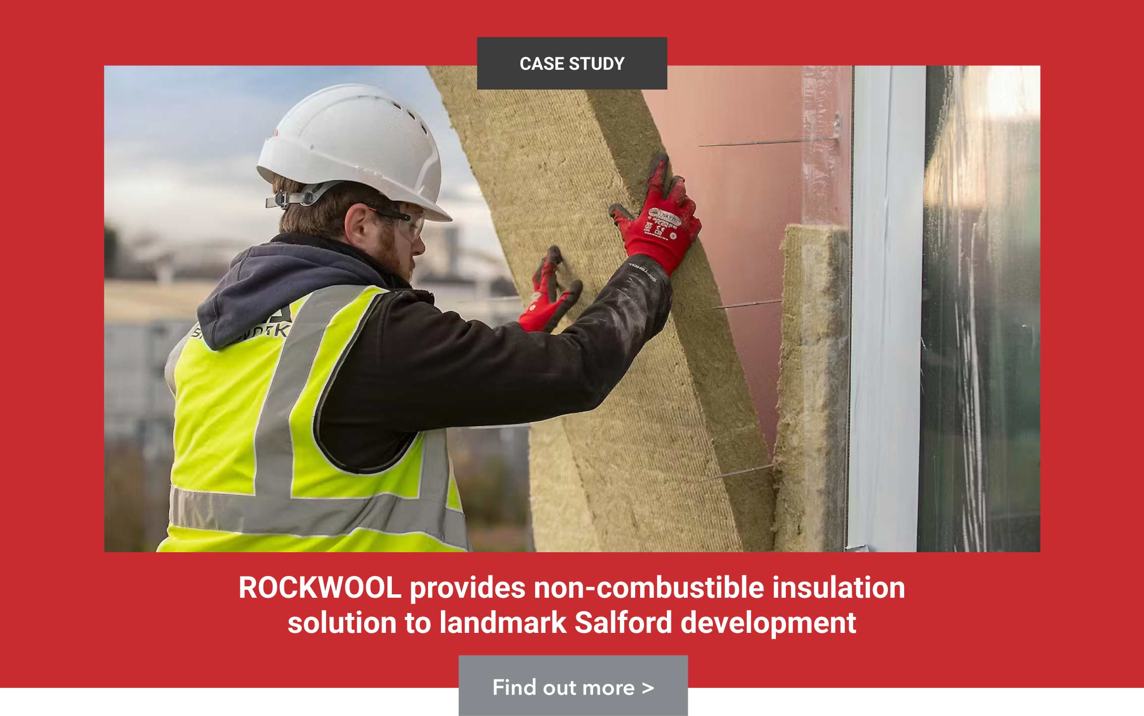 Construction worker installing Rockwool insulation panel on a building in Salford development project. 