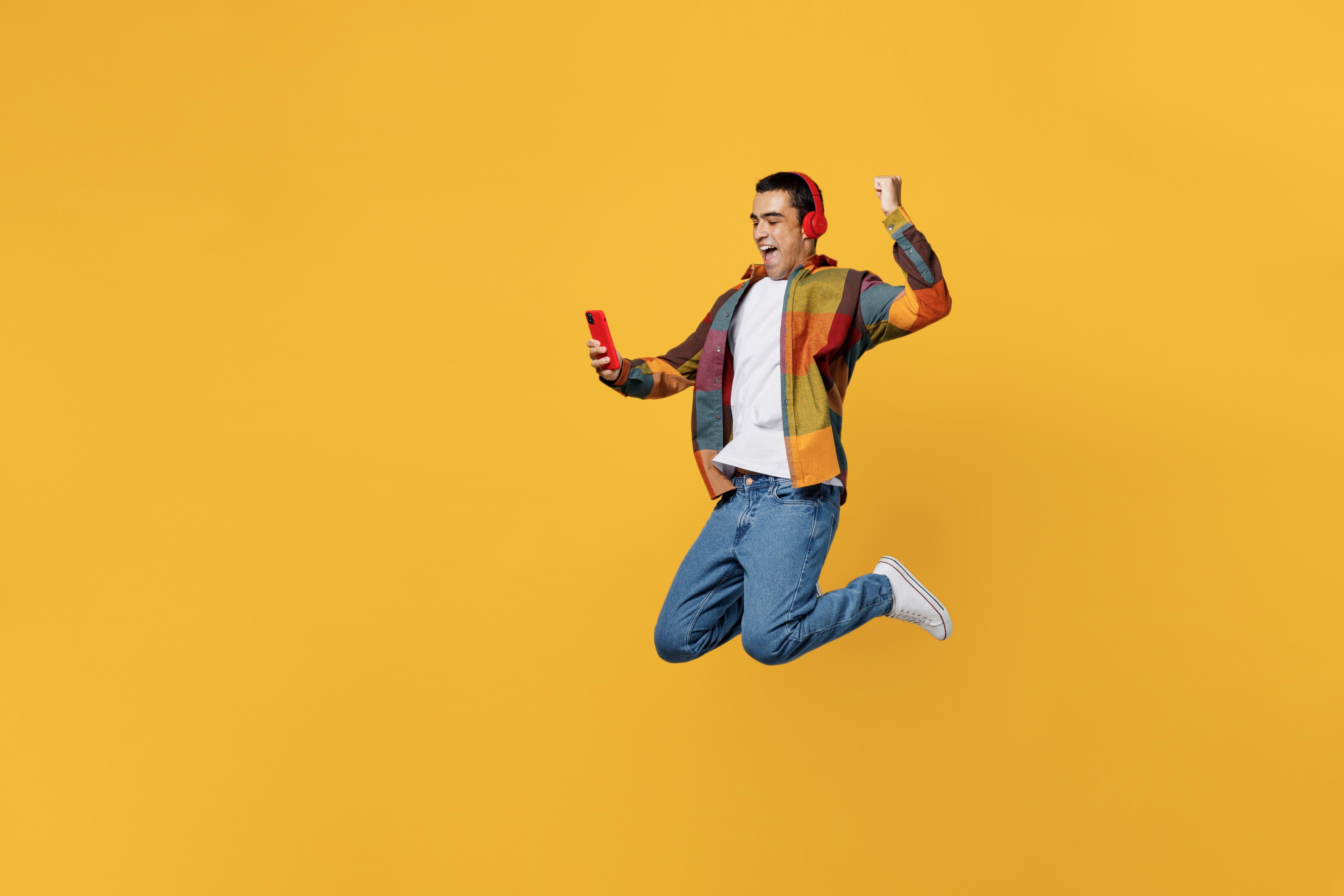 jumping, excited guy with headphones on a yellow background