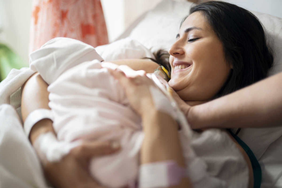 Mother breastfeeding newborn baby in hospital ward, first breastfeeding Mother breastfeeding newborn baby in hospital ward, first breastfeeding
