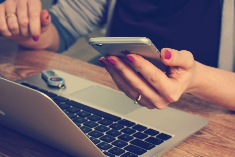 Woman using her iPhone and laptop