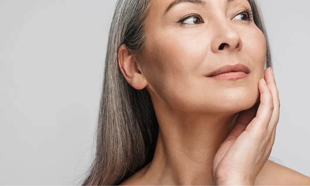 A mature woman smiling, featuring her radiant skin