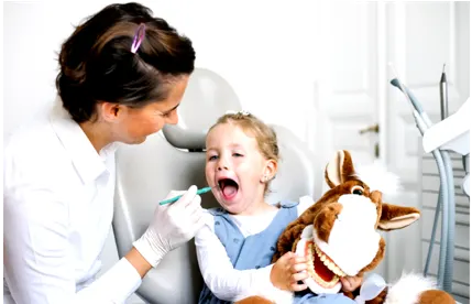 Kind bei Zahnarzt Untersuchung mit einem Stofftier