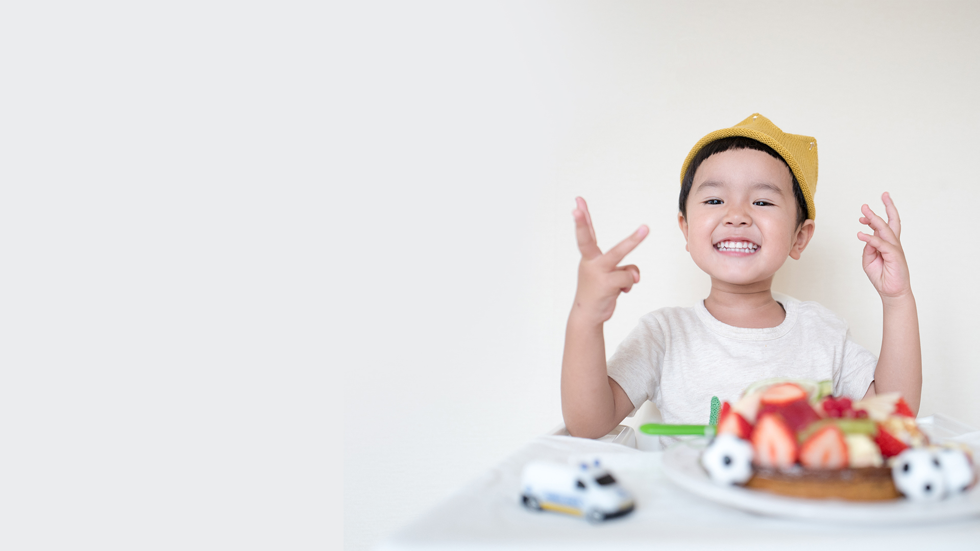 Child with cake and toys smiling.