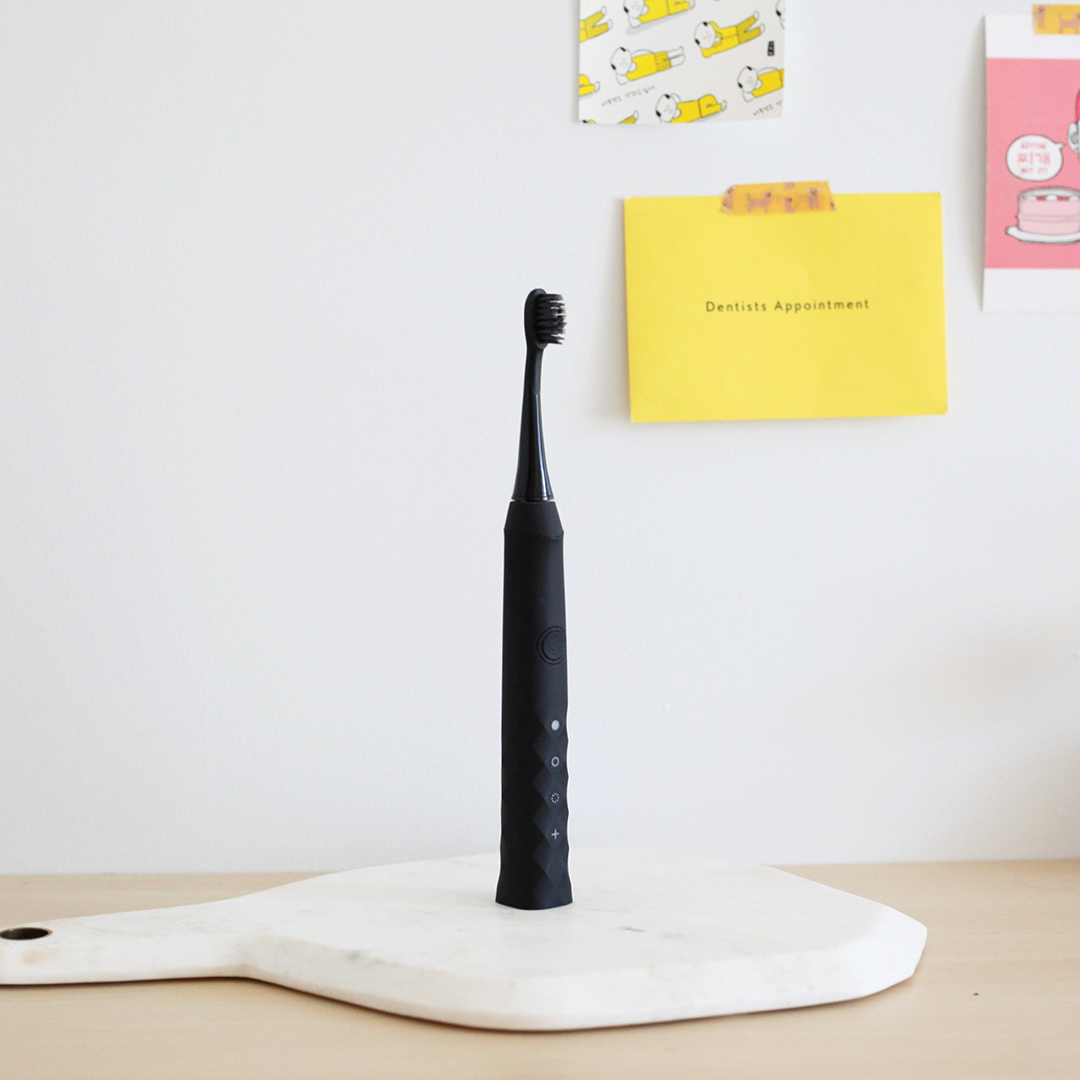 Black electric tooth brush on desk with sticky notes.