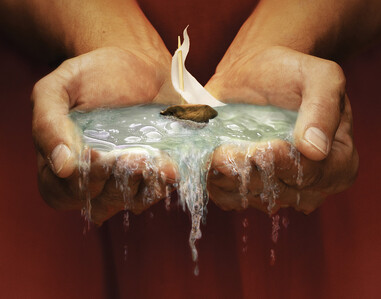 Two hands cupped together holding water with a small boat with a white sail floating on top.