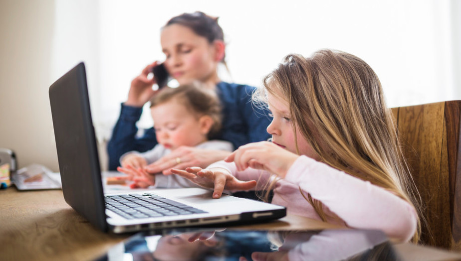 Niña usando la computadora con mamá al lado