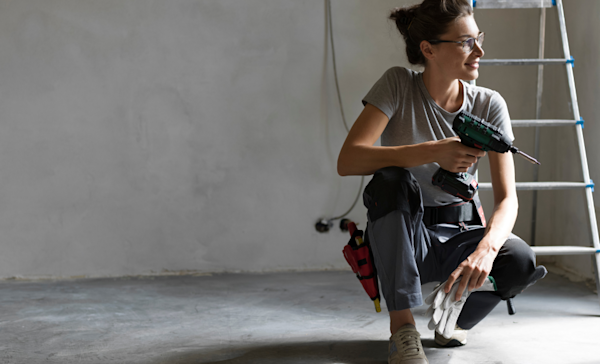 Professional repairwoman holding a drill and looking off into the distance