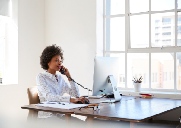 Young woman talking on phone at her desk in an office