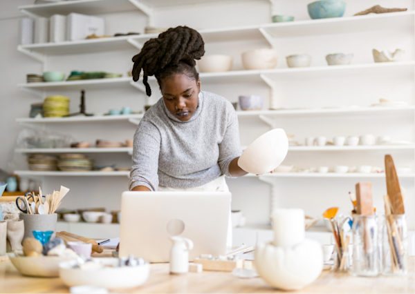 Woman working on her laptop in a pottery studio