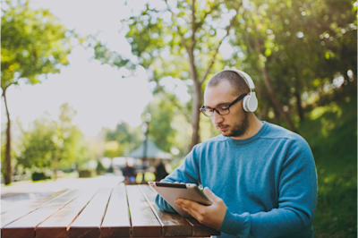 Young man looking down at tablet with headphones on