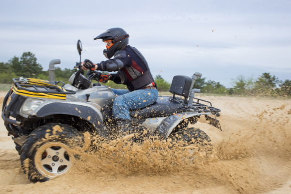 A person driving an ATV through sand