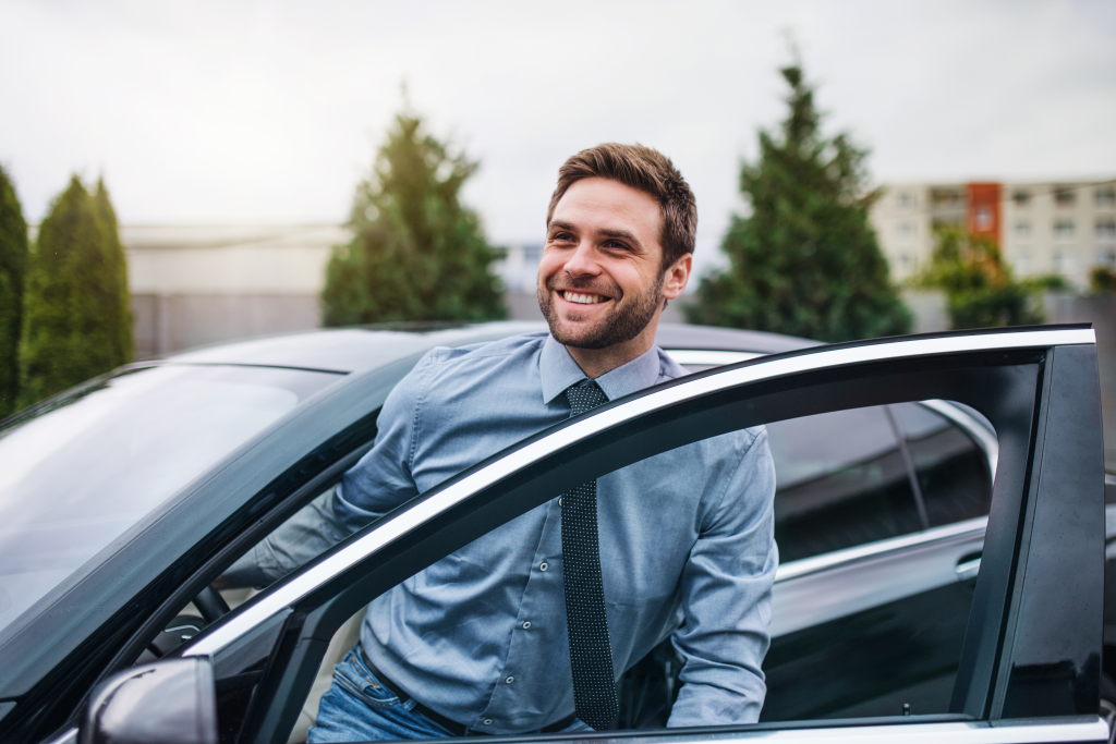 Smiling young man getting out of a car 