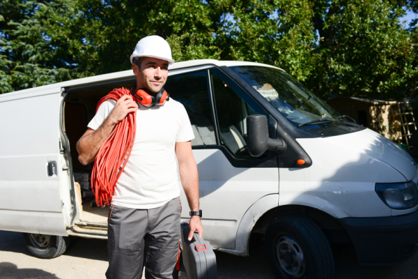 Young electrician taking tools out of his van